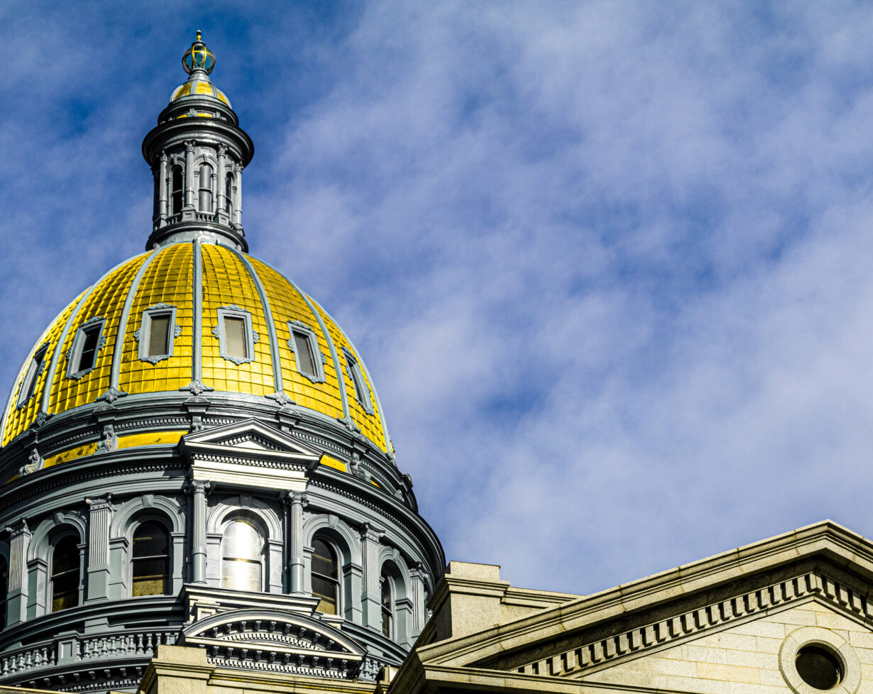 The golden dome of the Colorado State Capitol under a partly cloudy sky