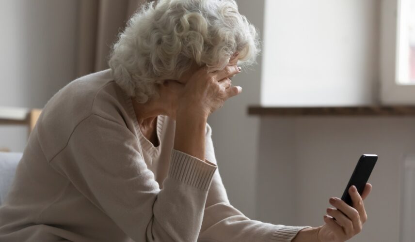 Elderly woman on the phone, holding her head in her hand