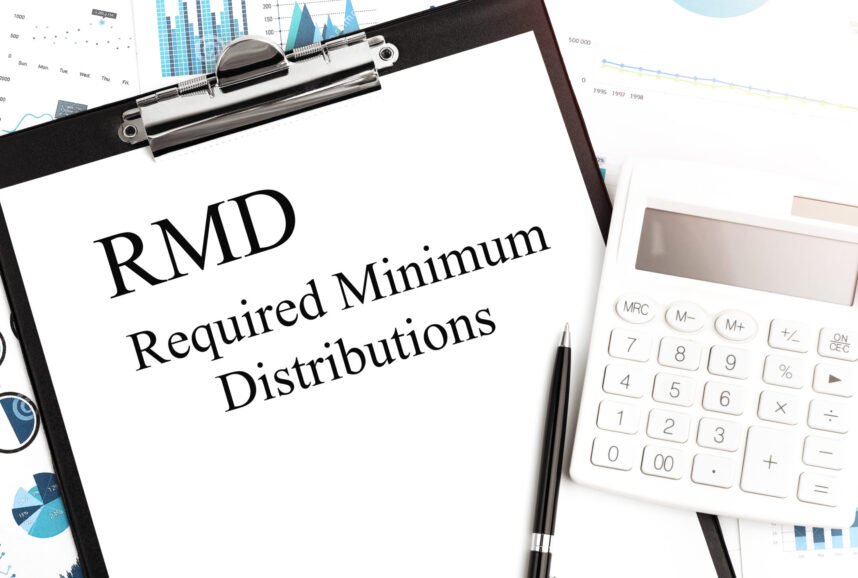 Text RMD Required Minium Distributions on clipboard. Calculator, pen, charts, documents and graphs on background.