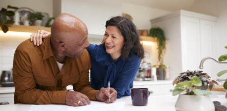 A man and woman standing at a kitchen counter and smiling