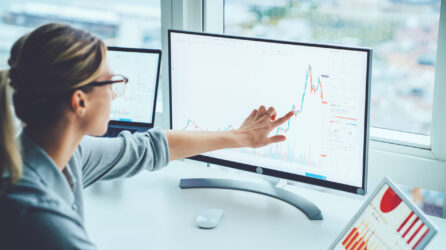 A woman pointing to a financial chart on a computer screen