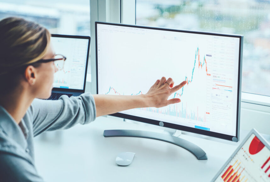 A woman pointing to a financial chart on a computer screen