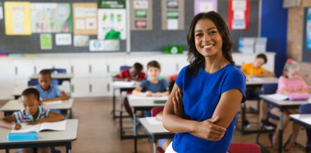 A smiling female teacher standing in front of her class