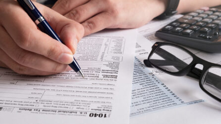 A closeup view of a person filling out a 1040 tax form