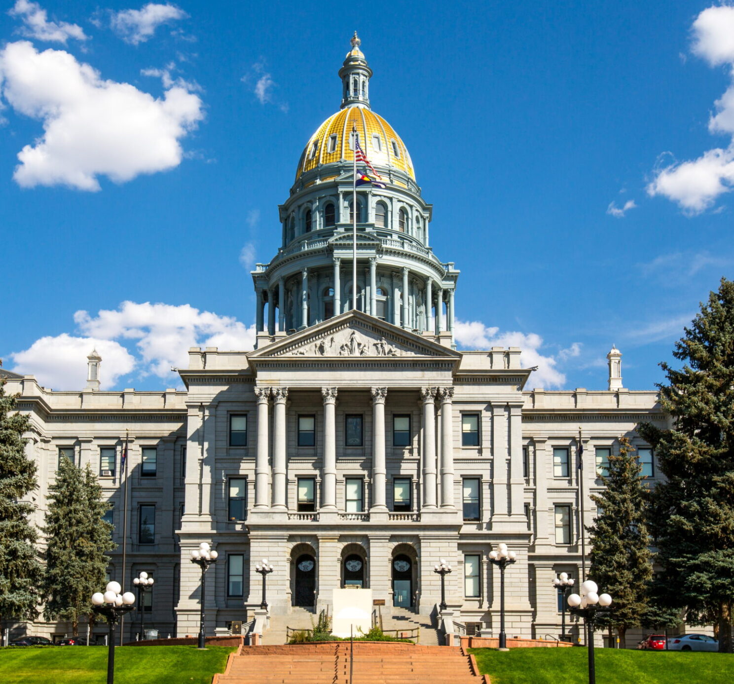 The Colorado State Capitol in summertime, framed by a green lawn and blue sky
