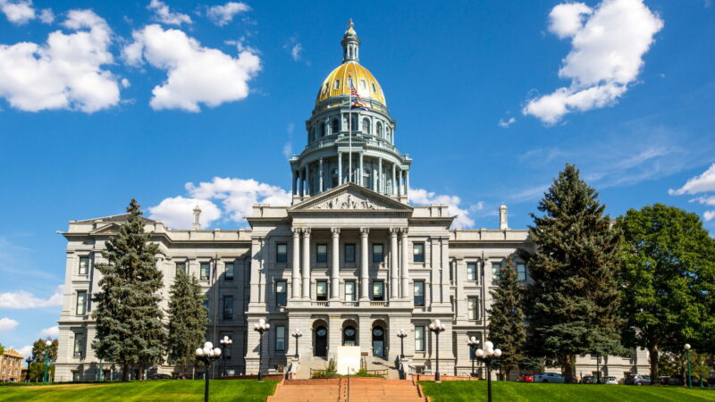 The Colorado State Capitol in summertime, framed by a green lawn and blue sky